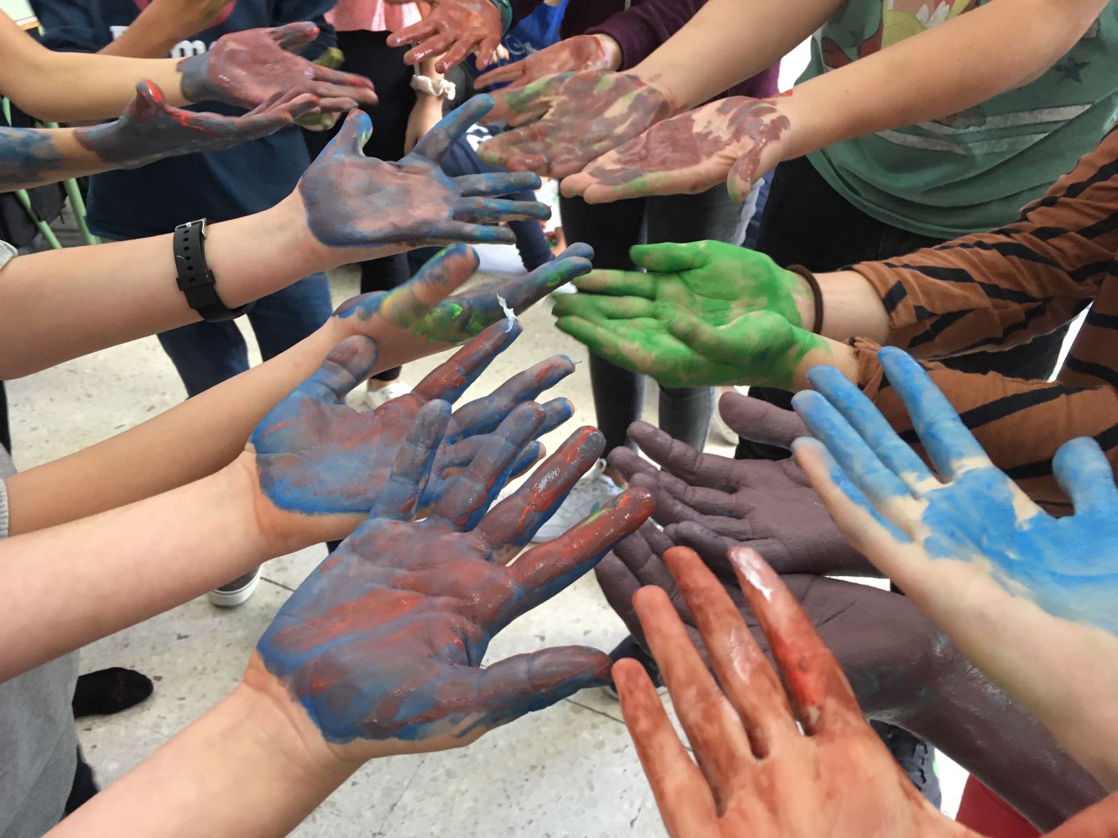 Las palmas de las manos de diferentes personas pintadas de distintos colores