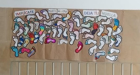 Un mural con huellas de pies pintadas bajo el título "deja tu huella"