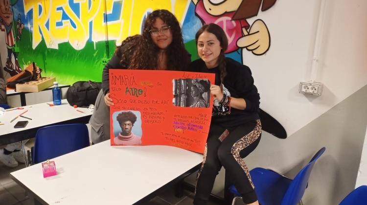 Dos chicas sujetan una pancarta con argumentos en contra de la discriminación a las personas afrodescendientes