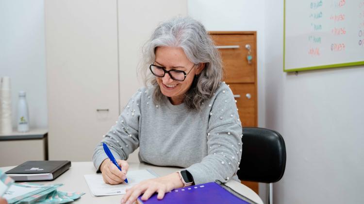 Una mujer sentada en una mesa escribiendo en un papel