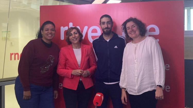 Cuatro personas posan de pie en un estudio de radio. Al fondo, en un cartel rojo se lee RTVE